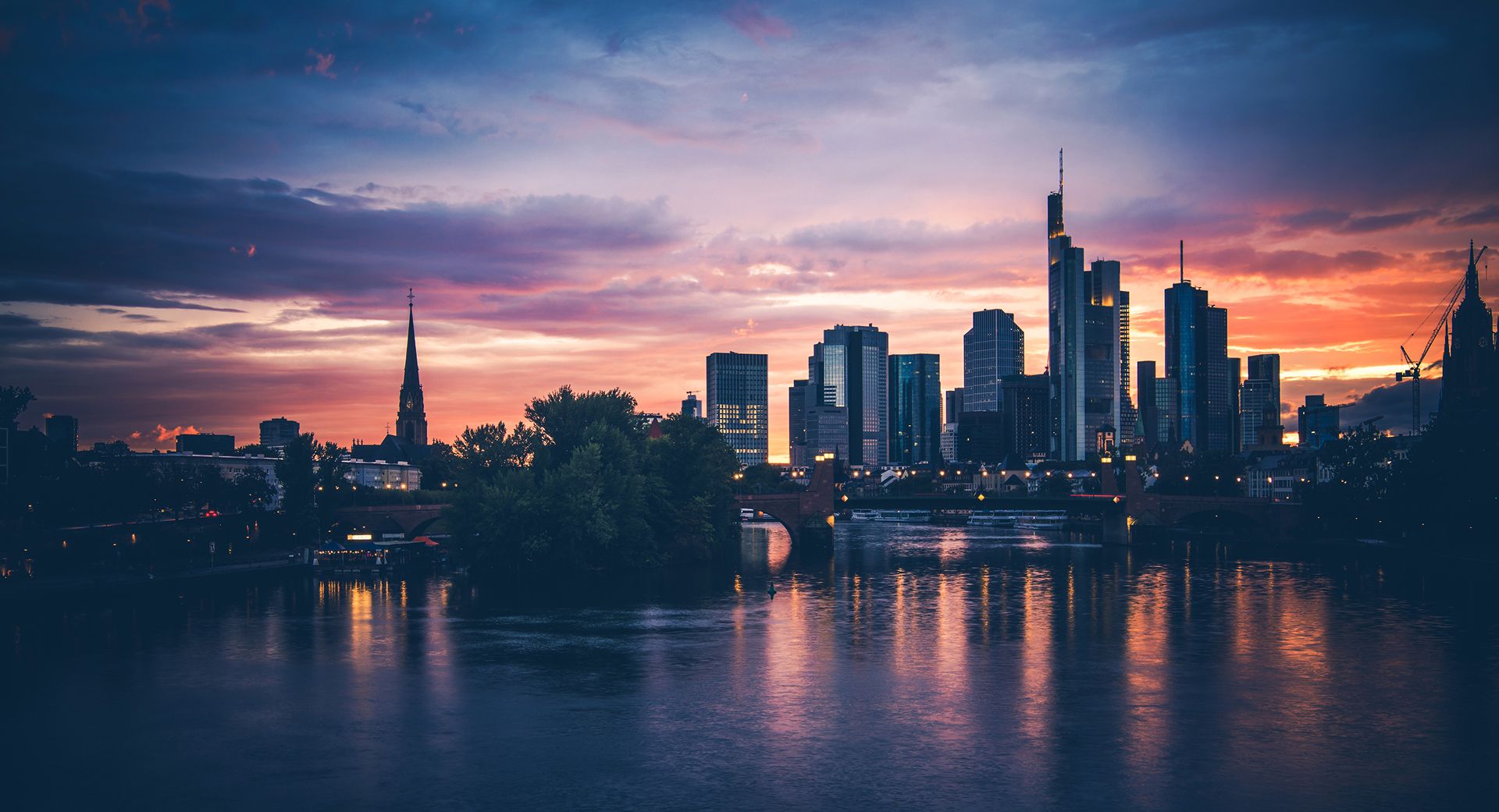 Frankfurter Skyline bei Sonnenuntergang mit Spiegelungen im Main